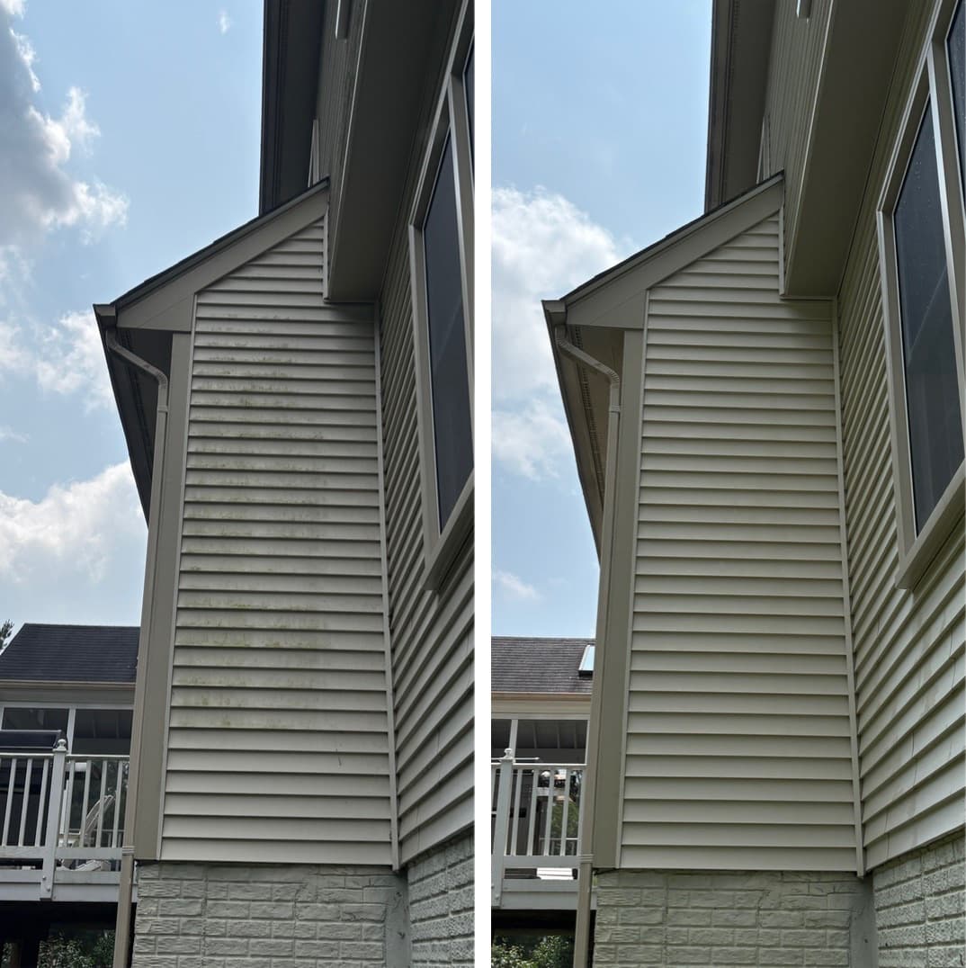 siding and soffit cleaning on an almond vinyl gable above a stone foundation, green algae removed, Maryland